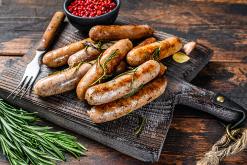 Grilling,Bavarian,Sausages,On,A,Cutting,Board.,Dark,Wooden,Background.